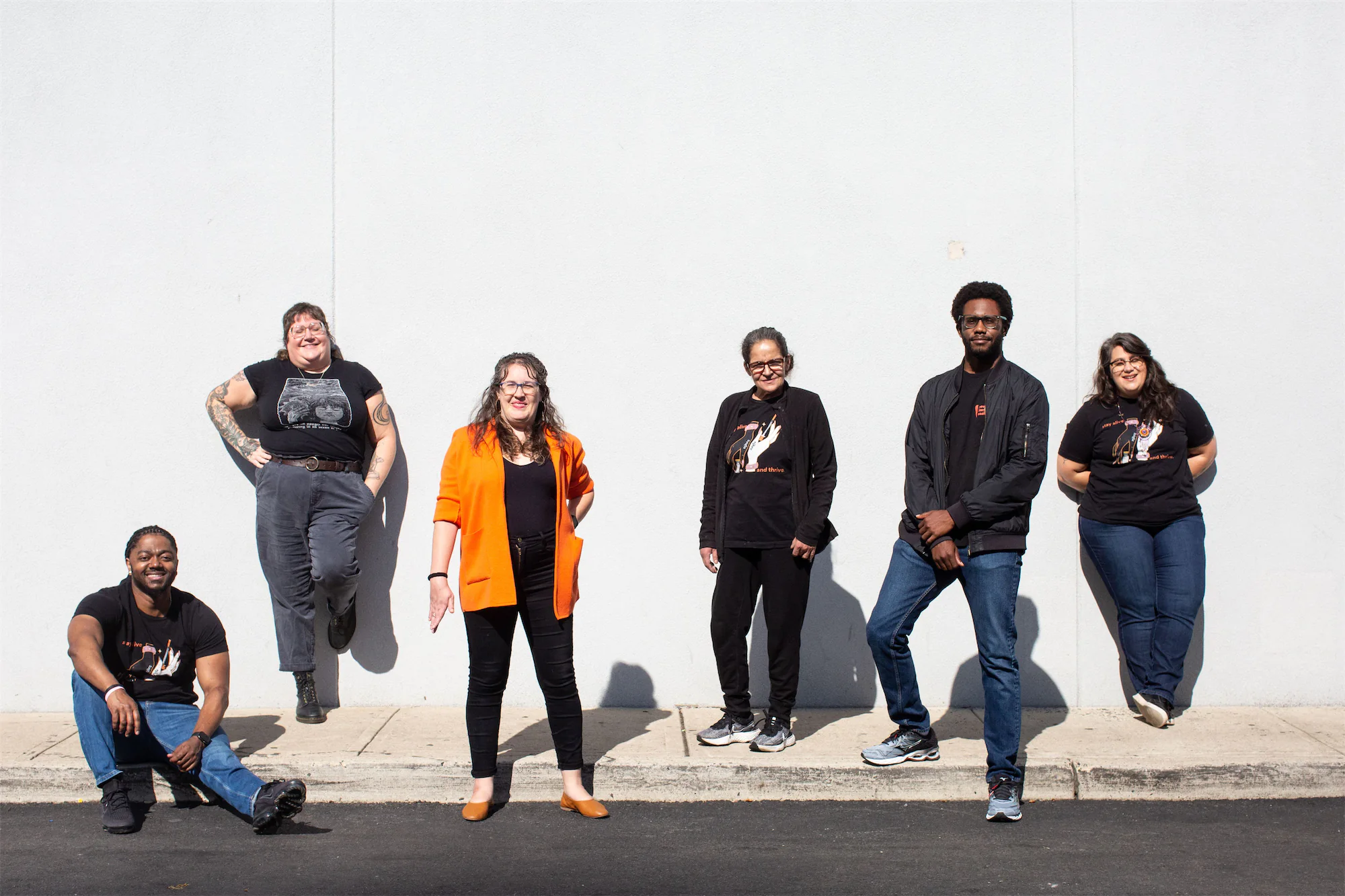 Group photo of 6 team members outside against a white wall